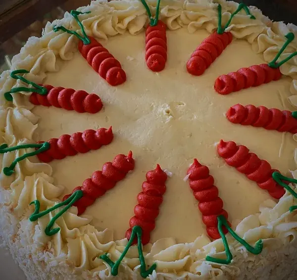 A whole carrot cake with cream cheese frosting and piped carrots, from the Chances R kitchen