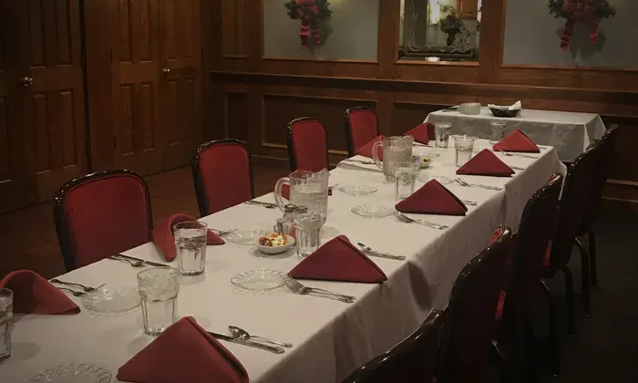 A long private-room table set with white linens and red napkins